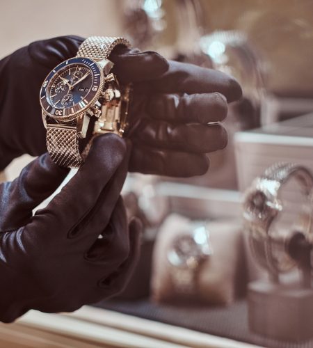 Close-up of the seller's hands in gloves shows the exclusive men's watch from the new collection in the luxury jewelry store