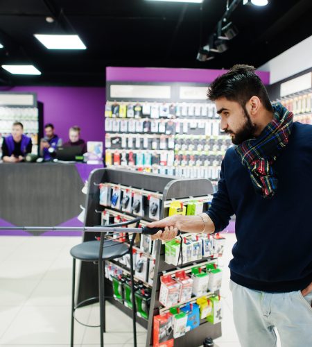 Indian man customer buyer at mobile phone store making selfie by smartphone on monopod stick. South asian peoples and technologies concept. Cellphone shop.